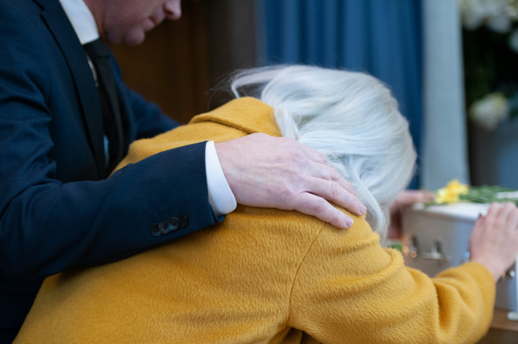 donna e uomo davanti a una bara momento di conforto
